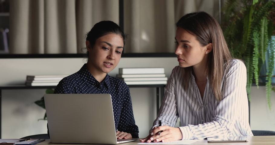 Focused millennial indian leader helping new worker with computer corporate software application in office. Motivated young mixed race employees developing project growth strategy, brainstorming ideas | Shutterstock HD Video #1071788746