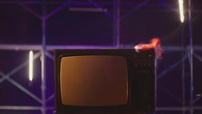 Old TV Set with big Screen in Fire . Old TVs burning on fire . Concept of modern technology , internet and anti-propaganda . Destruction of retro TV. 80s or 90s TV set blazing in slow motion
