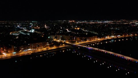 An aerial shot of the bright cityscape of Novi Sad in Serbia during nighttime, 4K footage