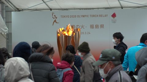 FUKUSHIMA, JAPAN - 24 MAR 2020 : Crowd of people at Olympic Flame display ceremony at Fukushima station. Tokyo Olympic 2020 have been postponed to 2021 due to coronavirus. Many people wearing masks.