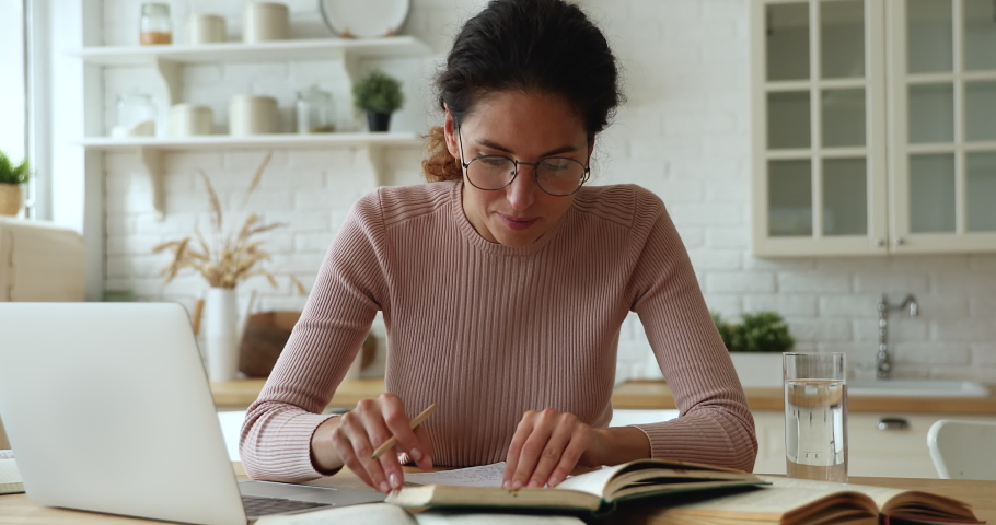 Serious focused woman reading textbook, hold pencil take notes, writes down useful information from printed educational literature, reducing thirst drink still water. Study, gain new knowledge concept Royalty-Free Stock Footage #1071802555