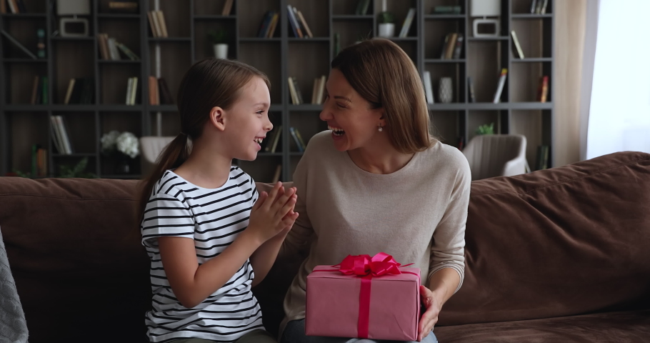 Family sit on sofa little daughter congratulates young mom International Women Day, prepare gift box, makes surprise express care, love and attention. Life event celebration, 8-march congrats concept Royalty-Free Stock Footage #1071802768