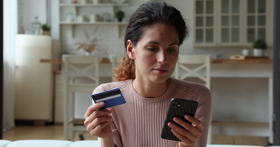 Woman holding credit card and smart phone experiences problems with e-payment. Female feels angry due lack of money, payment insecurity, insufficient, not enough funds. Victim of fraud, scam concept Royalty-Free Stock Footage #1071802885