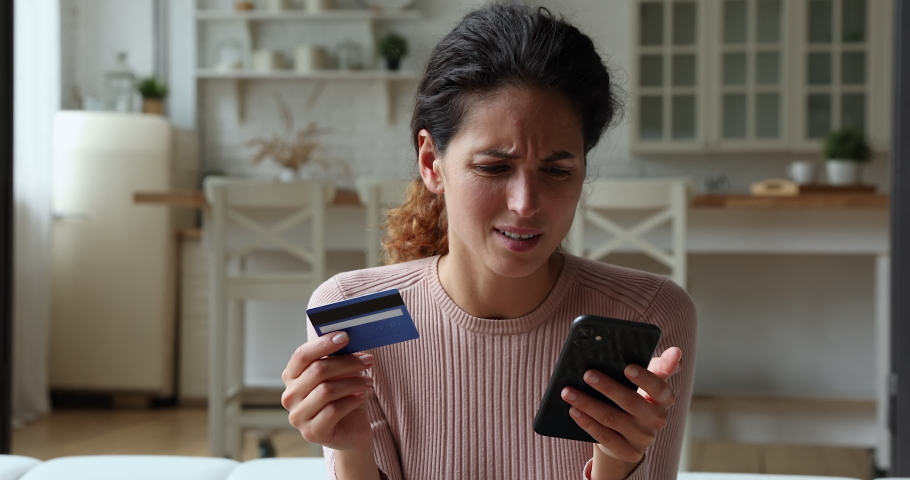 Woman holding credit card and smart phone experiences problems with e-payment. Female feels angry due lack of money, payment insecurity, insufficient, not enough funds. Victim of fraud, scam concept | Shutterstock HD Video #1071802885