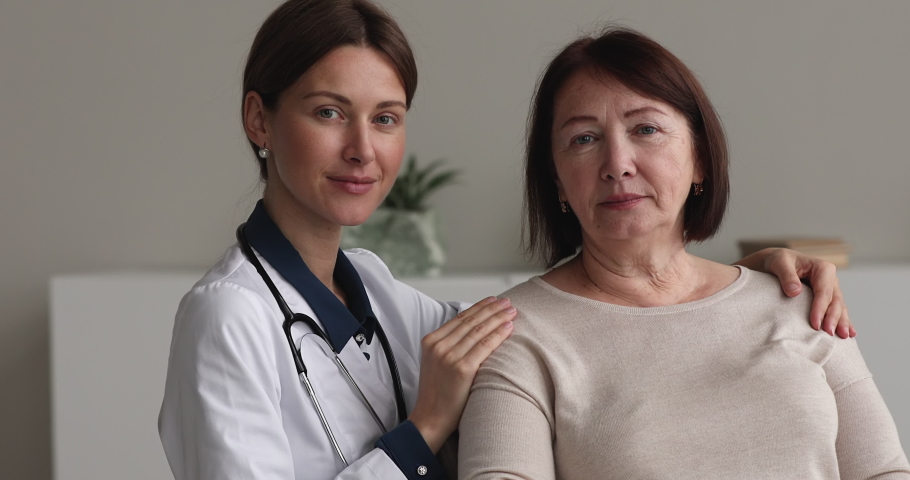 Portrait of pleased old female patient and young reliable therapist GP doctor pose in clinic office smile look at camera. Medical appointment, professional consultation at hospital, elder care concept | Shutterstock HD Video #1071803011
