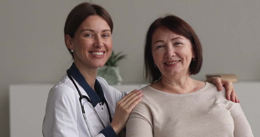 Portrait of pleased old female patient and young reliable therapist GP doctor pose in clinic office smile look at camera. Medical appointment, professional consultation at hospital, elder care concept Royalty-Free Stock Footage #1071803011