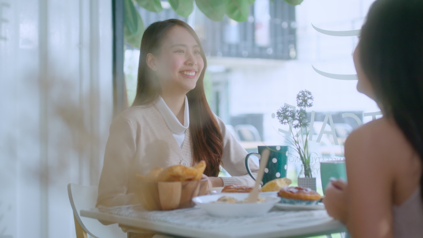 attractive asian female talking good positive conversation to friends with smiling laugh and happiness moment at counter near window at cafe with daylight from garden positive attitude relationship