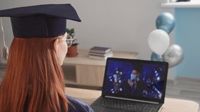 young adorable female student in academic dress attending online graduation with male teacher wearing medical mask, university rector uses modern video communication technology to graduate during