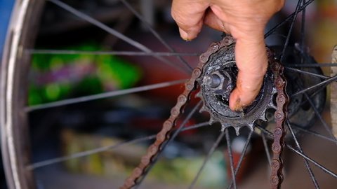 A mechanic hand is greasing the old bicycle gear plate for better repair and maintenance