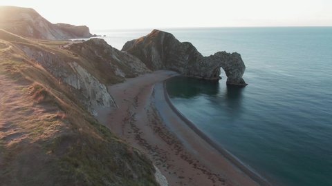 An amazing view of sunrise from the cliffs of Durdle door, Dorset, England showing natural limestone arch and a calm ocean