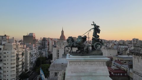 Aerial pan right of a bronze quadriga monument in front of Angrentine Congress Palace Dome at golden hour, Buenos Aires