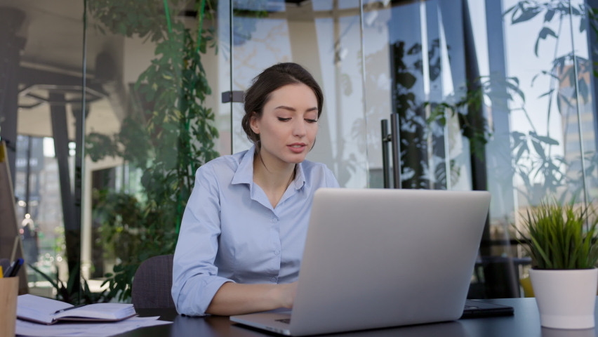 Young Brunette In The Office. She Is Sitting In Front Of Laptop Monitor. Girl Thinking About Something.