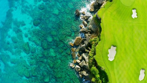Caribbean nature of the Dominican Republic. A bright green golf course with sandpits and a blue ocean background.