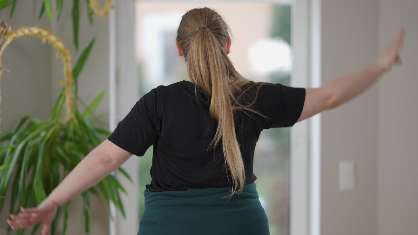 Back view of persistent overweight young woman training reaching hands behind back. Plump Caucasian yogi doing cow face yoga pose exercising at home in the morning. Yoga and sport concept