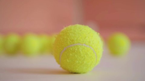 tennis ball close-up on the background of other balls in the training room. Sports equipment for classes and trainings. Many yellow bone balls. An old tennis ball with lint in a clean room.