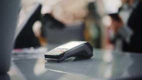 Clothing Store: Woman At Counter Buys Clothes Paying with Smartphone Through, Contactless NFC Terminal. Department Store, Shopping Center, Mall Purchase. Close-up Focus on Mobile Phone - Powered by Shutterstock - Get 15% off with code: PIKWIZARD15