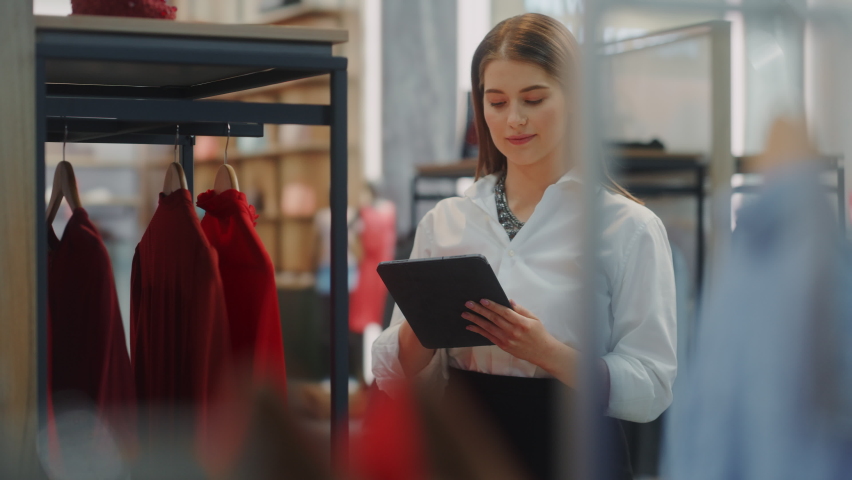 Clothing Store: Female Visual Merchandising Specialist Uses Tablet Computer To Create Stylish Collection. Fashion Shop Sales Retail Manager Checks Stock. Small Business Owner Orders Merchandise
