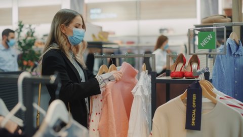 Beautiful Female Customer Wearing Protective Face Mask Shopping in Clothing Store. Diverse People in Fashionable Retail Shop, Choosing Stylish Clothes, Colorful Sustainable Brand Designs. Medium Shot
