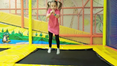 a girl jumps on a trampoline. the child spends time in Children's playroom.