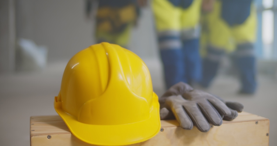 Close up of builder putting safety hardhat and gloves on wooden box. Cropped shot of construction worker leaving uniform at construction site and going home in evening Royalty-Free Stock Footage #1071836884