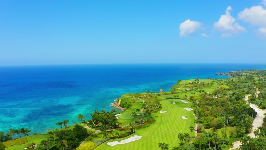 Golf course aerial 4k view stock video footage. Bright glade with green grass and Caribbean sea landscape. Beautiful planet earth top view. Royalty-Free Stock Footage #1071838183