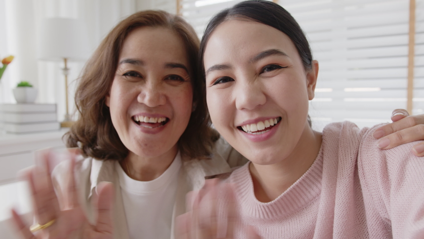 POV family retired healthy mom and girl two people waving hand greeting selfie look at camera on webcam app at relax comfort sofa couch living room in health care quarantine social distance isolate. Royalty-Free Stock Footage #1071839656