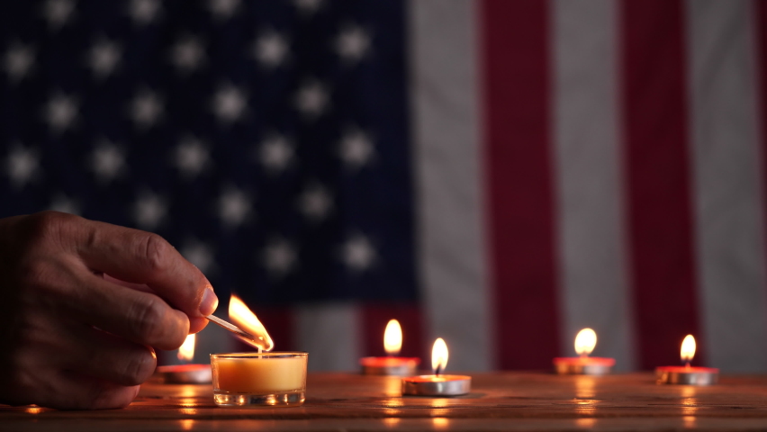 Memorial Day, Man hand light a candle for honoring and mourning with American flag background. Concept of Memorial Day or 4th of July, Independence Day, Veterans Day, American Celebration, USA flag.