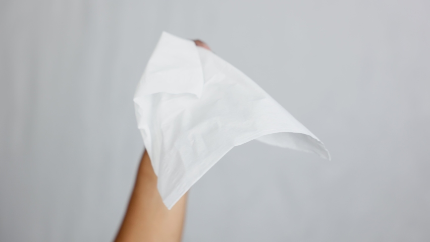 A close-up of a hand holding a white cloth waving back and forth, showing the meaning of surrendering.