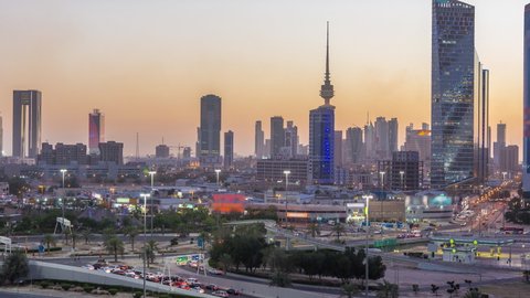 Skyline with Skyscrapers day to night transition timelapse in Kuwait City downtown illuminated at dusk. Aerial view from rooftop. Kuwait City, Middle East.