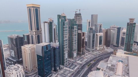 Skyline of the West Bay area from top in Doha day to night transition timelapse, Qatar. Illuminated modern skyscrapers aerial view from rooftop atevening after sunset. Traffic on the road