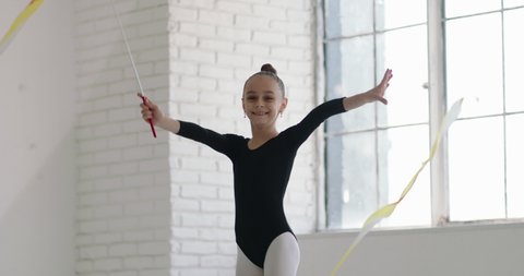 Teen girl wearing black leotard dancing. Young gymnast practicing moves and elements with a ribbon - childhood dream 4k footage