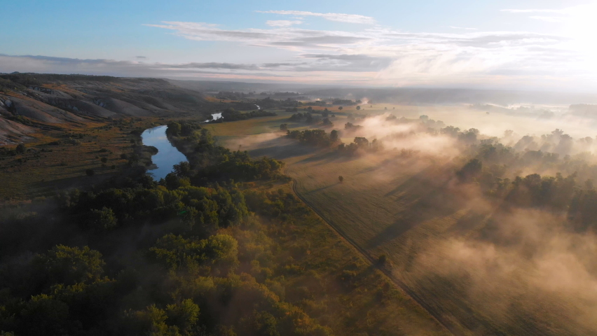 Aerial drone view of sunrise over misty river | Shutterstock HD Video #1071853099