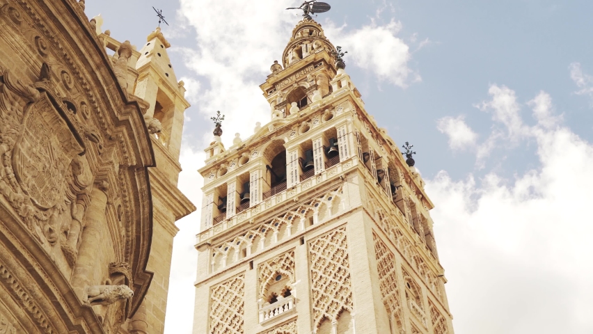 Discovering the Giralda in Seville behind some orange trees under a blue sky | Shutterstock HD Video #1071854185