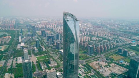 Suzhou, China - September 04, 2020: Aerial orbital view of a skyscaper under construction with reflections on the glass windows in a business district of Suzhou, China. IFS building.