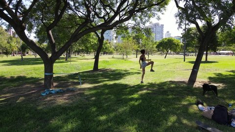 Young female balancing on slackline at the park in a sunny day