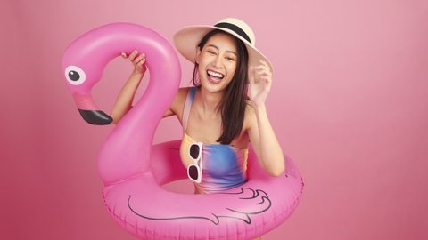 Beautiful Sexy asian woman in bikini and smiling standing  on pink background isolated .Summer vocation happy trip concept.