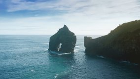 Aerial shot of rocky cliffs in Atlantic ocean, Casa do Gato Tomas, Flores Island, Azores, Portugal, Europe. Mountains washed with blue ocean waters. Natural landscape background, 4k footage 