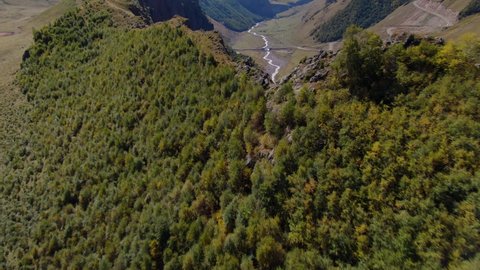 Aerial forward alpine road serpentine way, cars ride. Old bridge over river among epic North Caucasus mountains. National park natural landscape, rocky ridge peaks. Russia travel summer trip. Stock