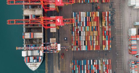 AFRICA,SOUTH AFRICA,CIRCA 2021.Straight down aerial view of shipping containers being loaded onto a container ship at Durban harbour, South Africa