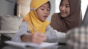 asian muslim mother help her daughter to learn online using laptop studying from home