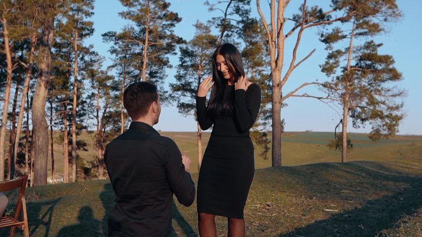 The man, in love and happy that the woman had said yes, put the ring on her finger in exalted form. The surprised woman looks at the ring and then offers a sincere kiss to her boyfriend. The portrait