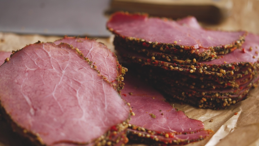 Delicious peppered roast beef pastrami slices on paper with grains of coloured pepper Royalty-Free Stock Footage #1071886243