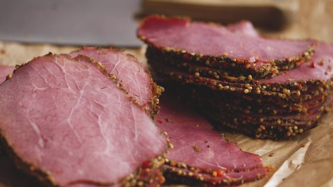 Delicious peppered roast beef pastrami slices on paper with grains of coloured pepper