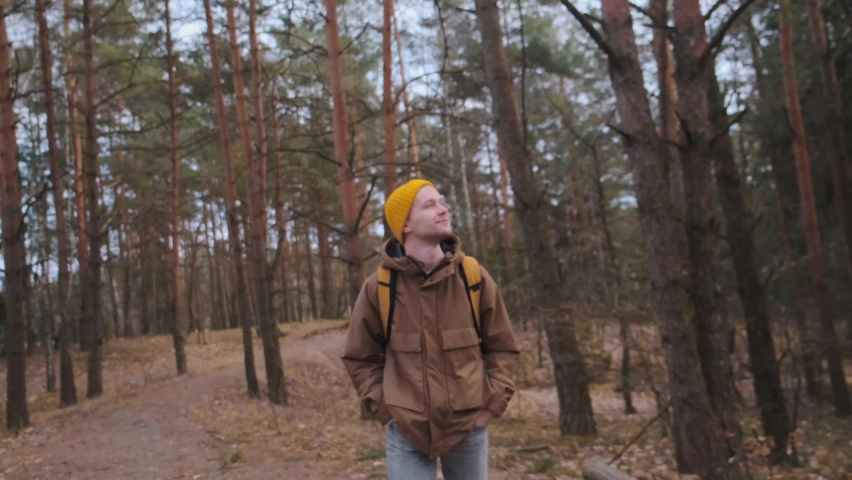 Young happy beautiful male smiling standing on the forest road. Travelling.