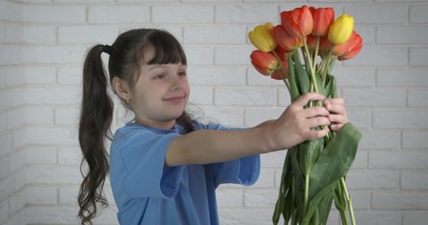 The kid gives flowers. Beautiful little girl gives a bouquet of tulips. 8 March, Mother's Day.