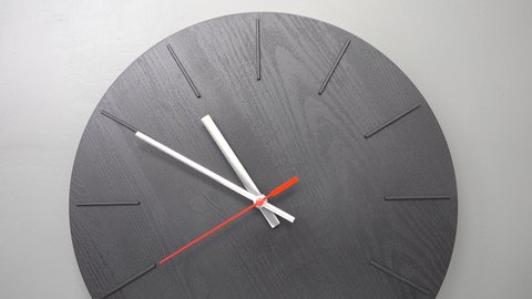 minimalistic black wall clock with red second hand on gray background