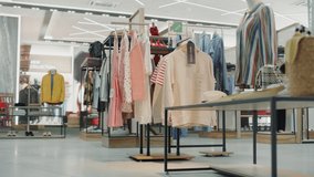 Shopping Clothing Store Interior. Modern Fashionable Shop, Clothes for Every Taste. Stylish Brand Design, Fashionable Colors, Quality Sustainable Materials. No People. Low Dolly Establishing Shot