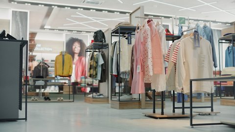 Shopping Clothing Store Interior. Modern Fashionable Shop, Clothes for Every Taste. Stylish Brand Design, Fashionable Colors, Quality Sustainable Materials. No People. Low Dolly Establishing Shot