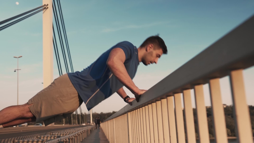 Sports and healthy lifestyle. Young man doing push-ups in city. Picture of a young athletic man doing push ups outdoors.