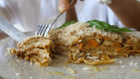 Traditional italian cuisine in vegan version. Person cuts a piece of a plant based lasagne and shows it to the camera